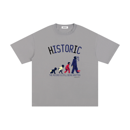 BORNGOATD Historic Evolution Gray graphic t-shirt featuring generational progression artwork and “The Record Is Still Being Written” slogan