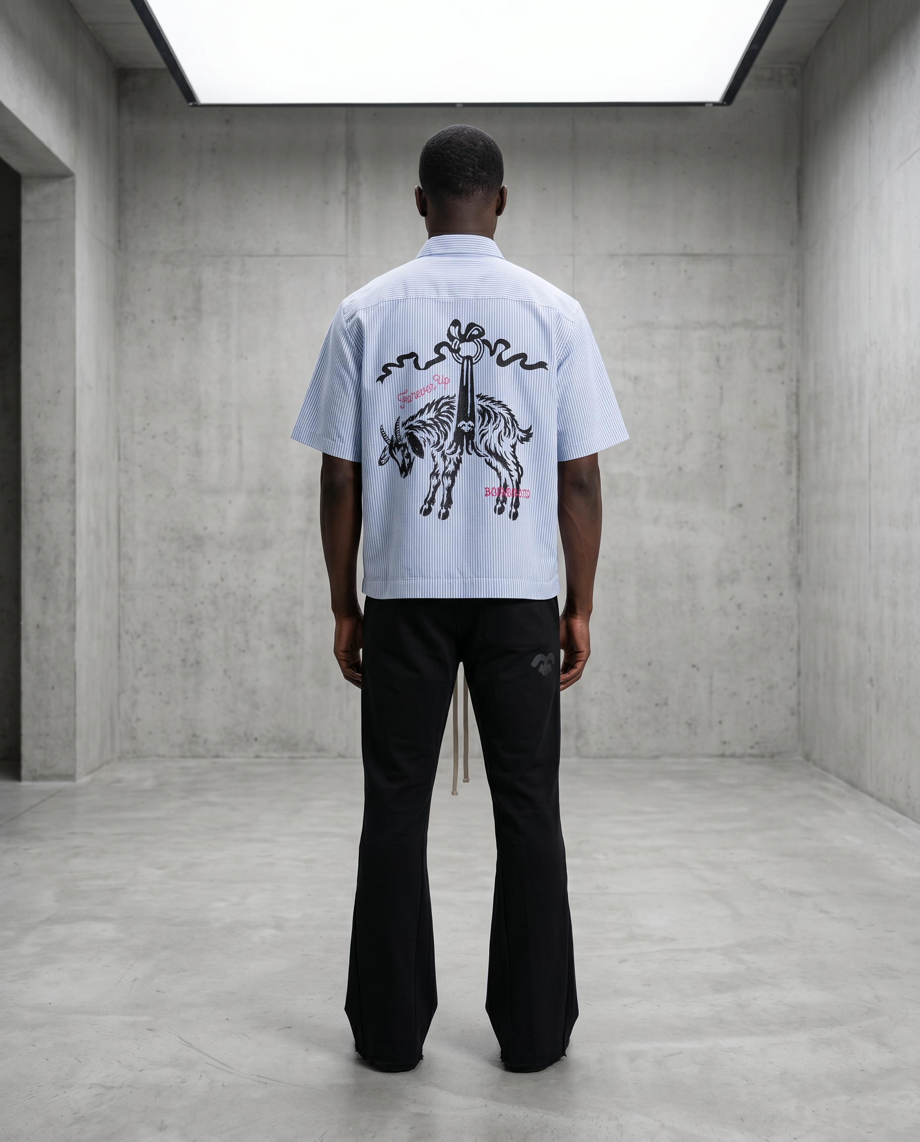 Person wearing a white t-shirt with a graphic design in a minimalistic room.