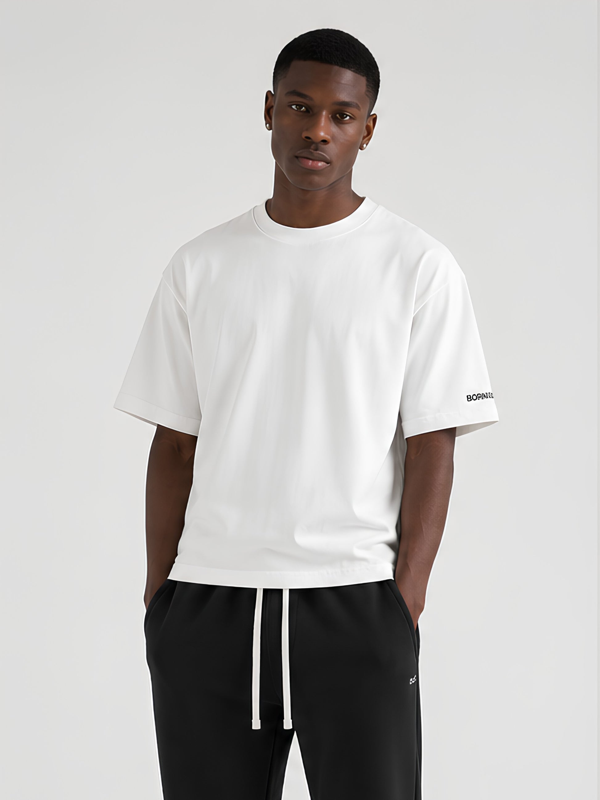 A man wearing a white short-sleeve BORNGOATD Daily Tee-shirt with a small black BORNGOATD logo